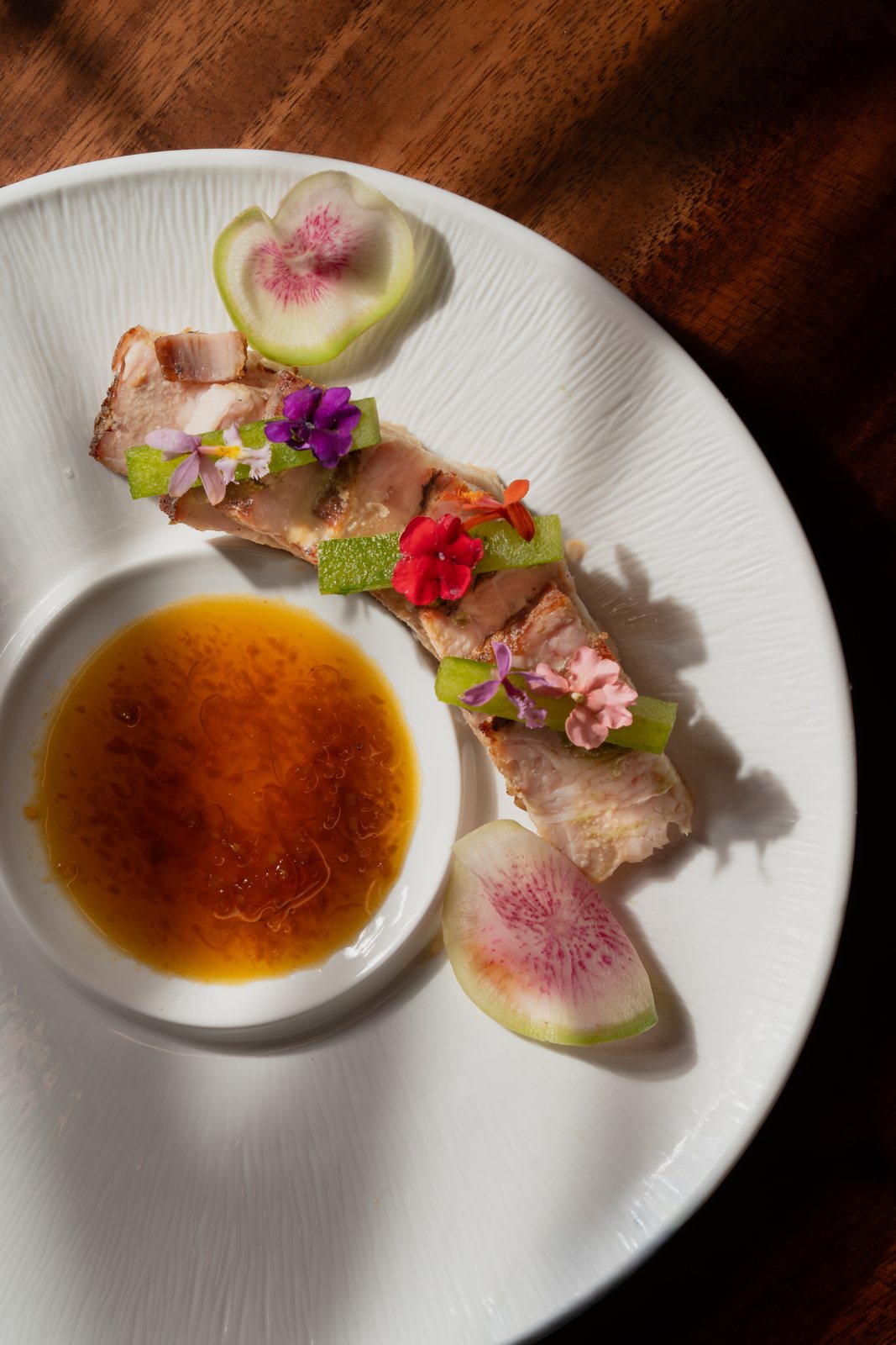 Pork Belly with watermelon radish, edible flowers and ginger citrus sauce at MUI Supper Club