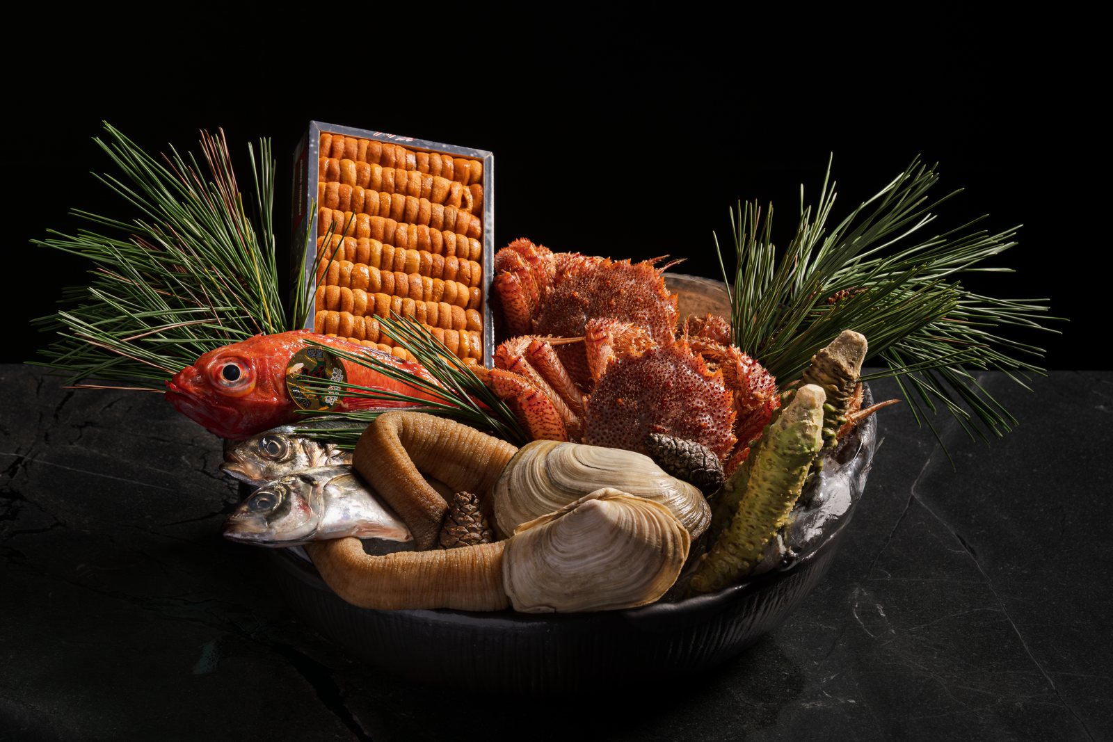 A box of Toyosu Market seafood at MUI Supper Club: uni, crab, kinmedai, geoduck and fresh wasabi among pine