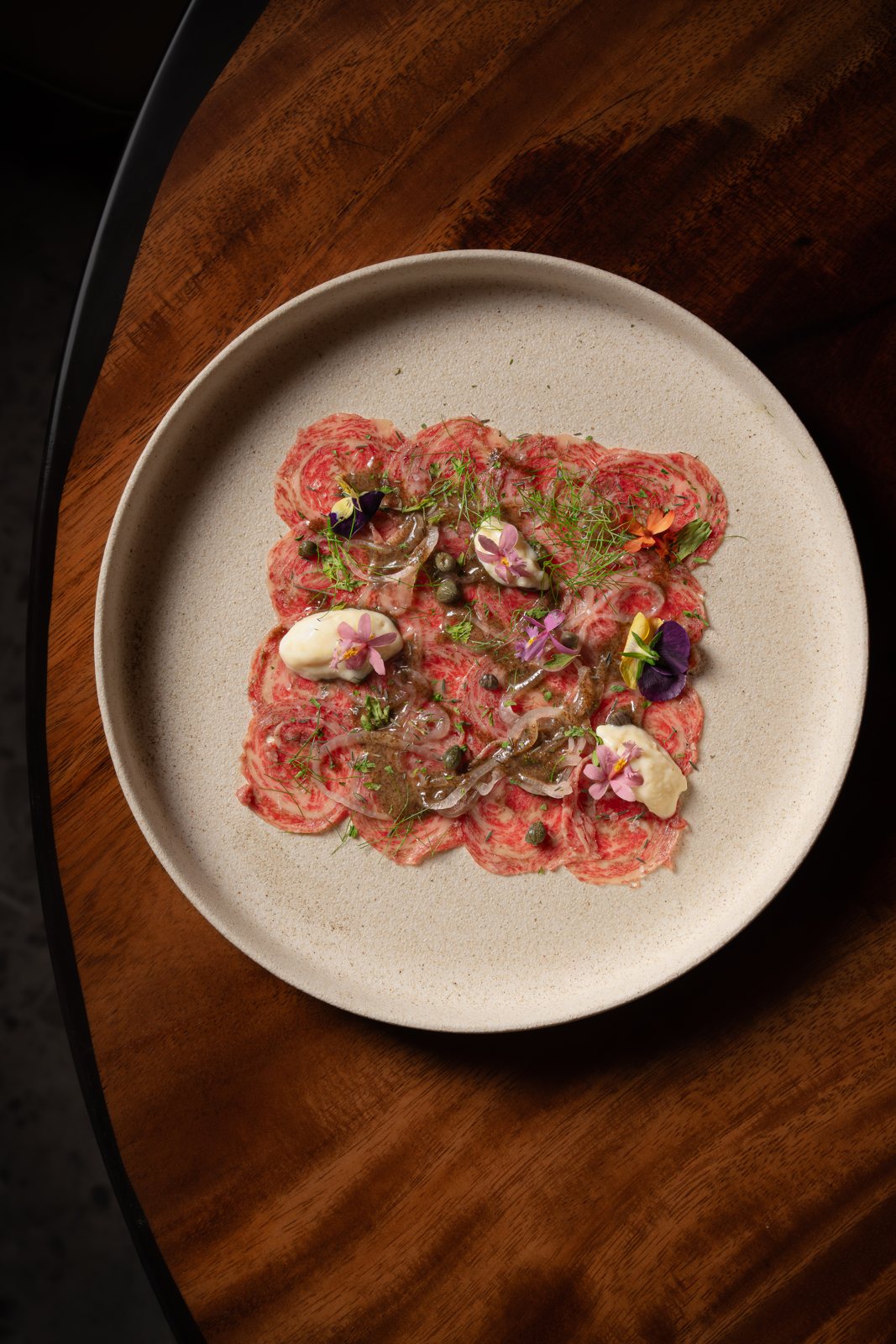 Wagyu Carpaccio with capers, herbs, aioli and edible flowers at MUI Supper Club