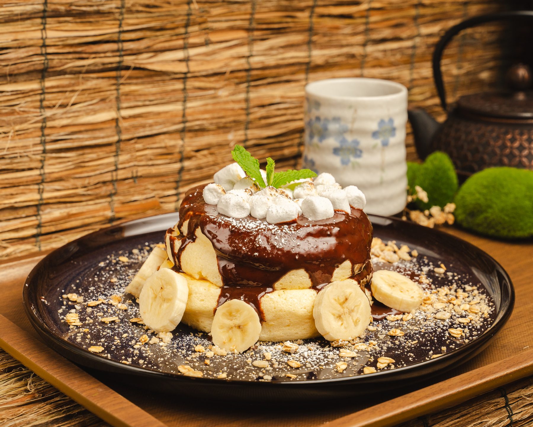 A choco banana soufflé pancake glazed with chocolate and topped with marshmallows and mint, ringed by banana slices, at Okaeri Japanese Cafe in Centreville, VA